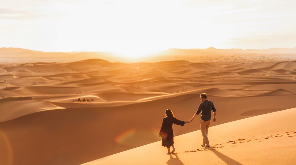 Couple walking through sand dunes