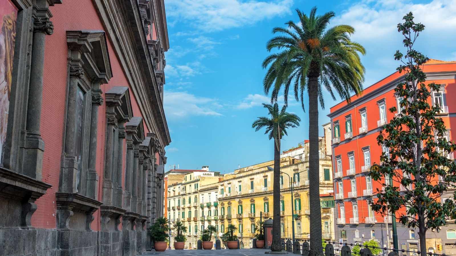 Colorful and beautiful architecture with palm trees in front of the National Archaeological Museum in Naples, Italy