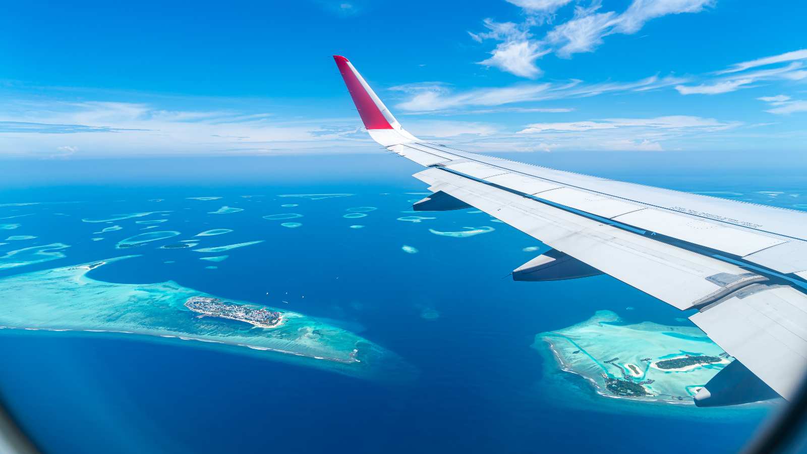 Maldives islands top view from airplane window with airplane's wing