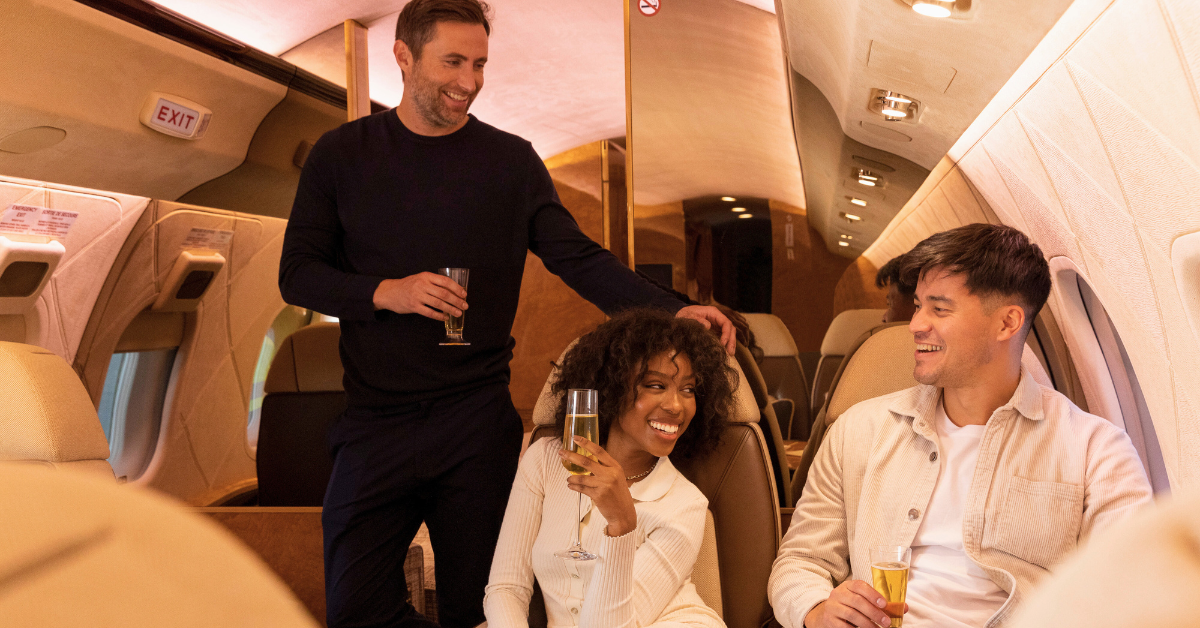 woman and two men smiling and holding champagne inside private jet